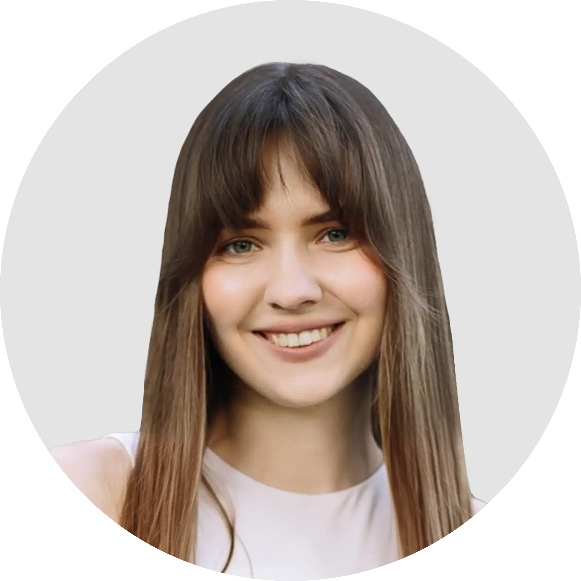 Young woman with long dark hair, bangs, smiling gently, wearing a light top.