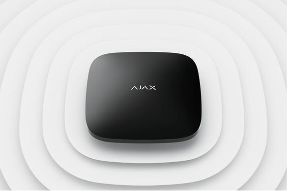 Black square smart home hub with 'AJAX' logo on a white concentric pattern background.