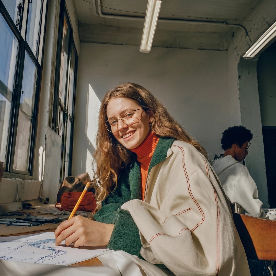 Student writing at a desk in a sunlit room