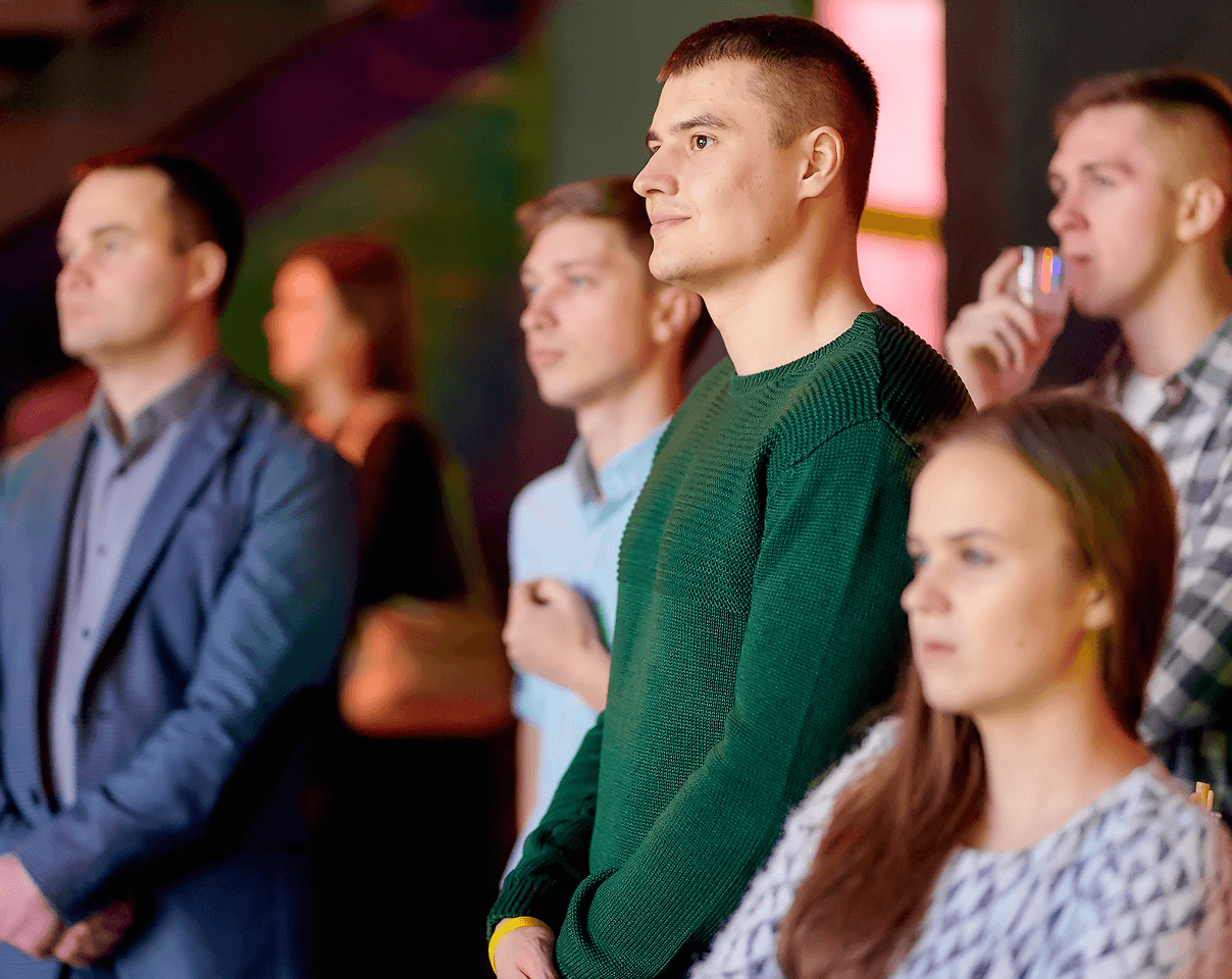 A diverse group of people attentively watching an event with focused expressions.