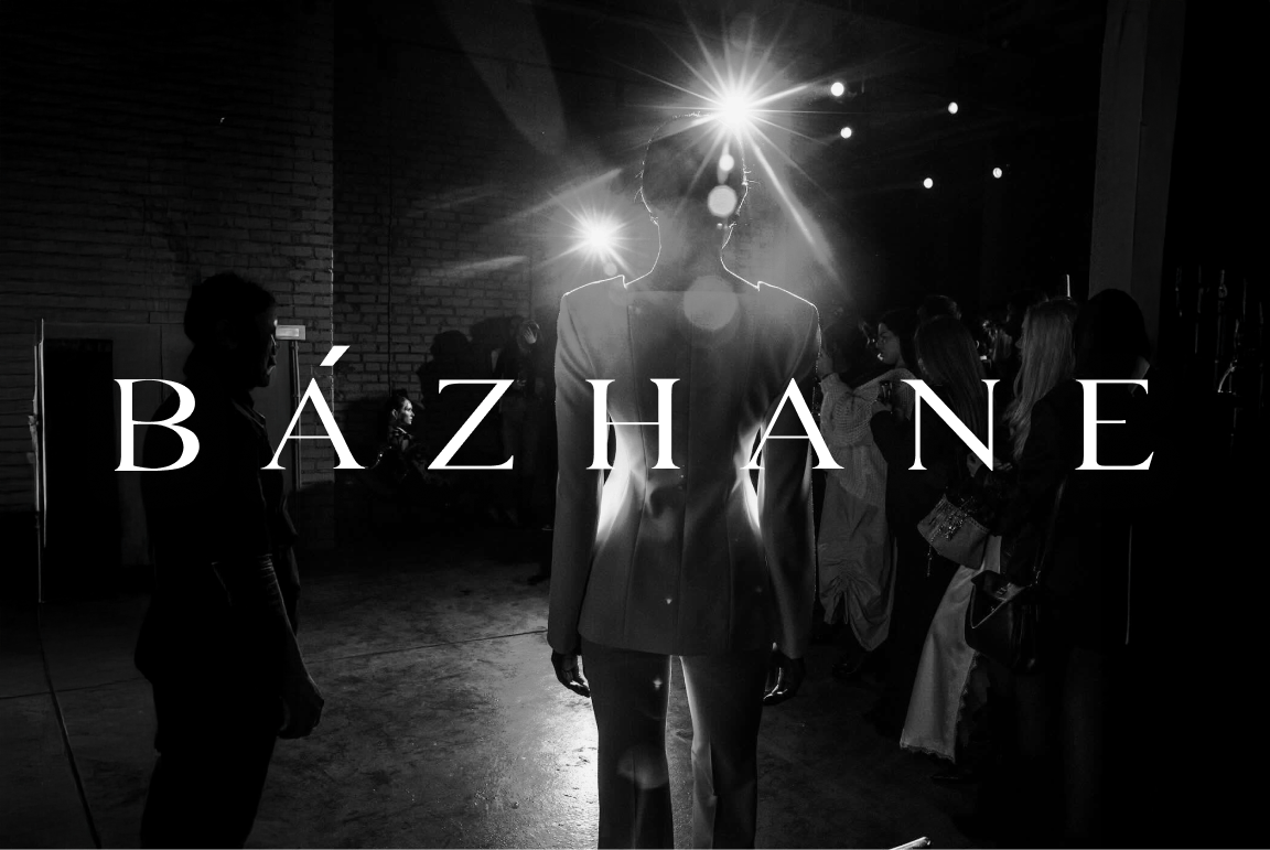 BÁZHANE text overlays a person in a dark room, silhouetted by bright spotlights.